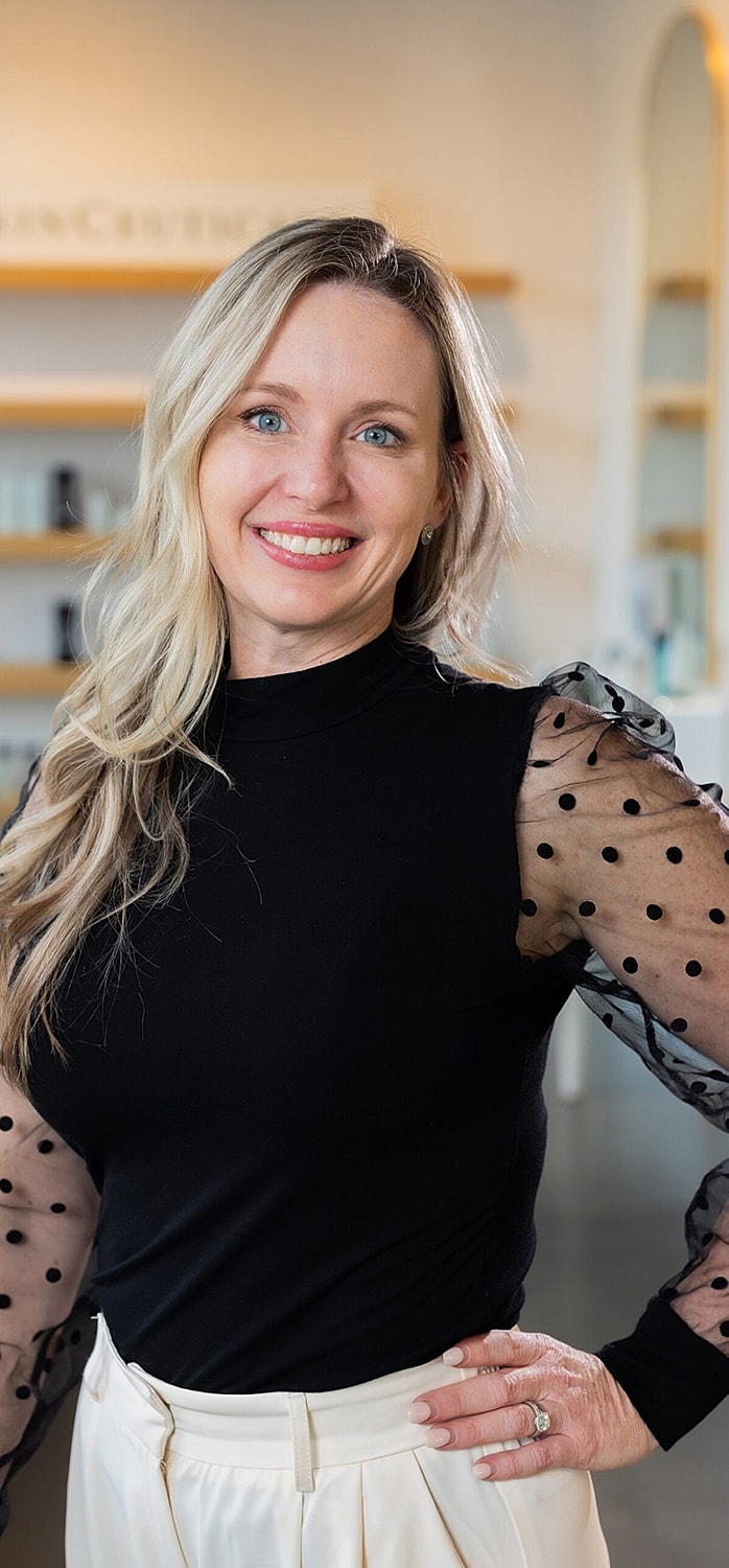 Smiling woman with long hair wearing stylish outfit.