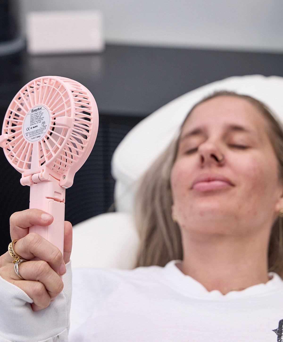 Person using a portable pink fan.