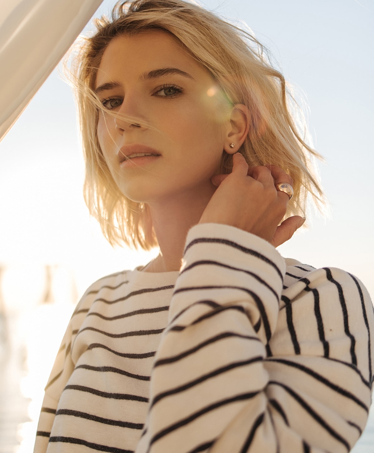 Woman in striped sweater with sunlight backdrop.