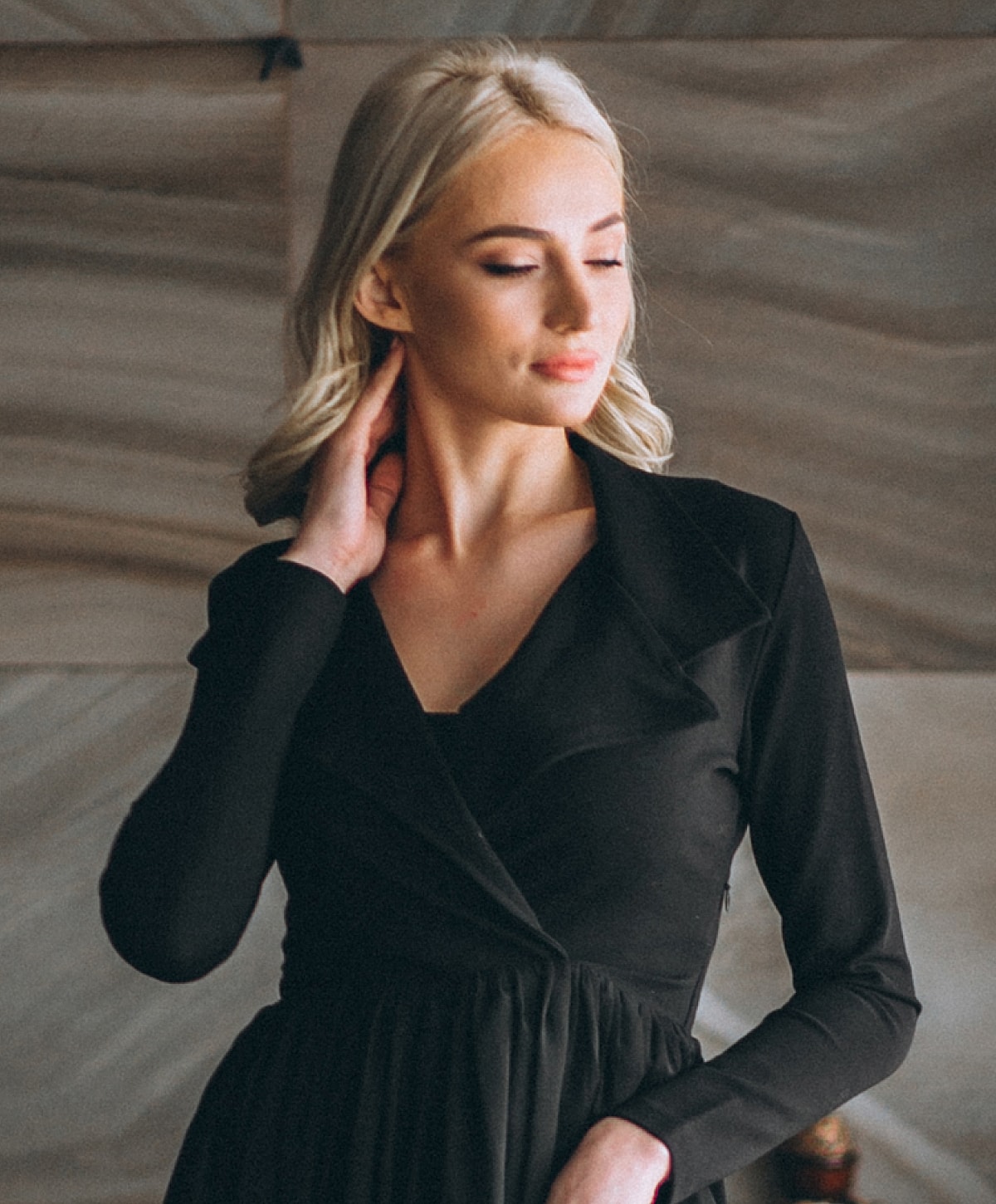Woman in elegant black dress, relaxed pose.