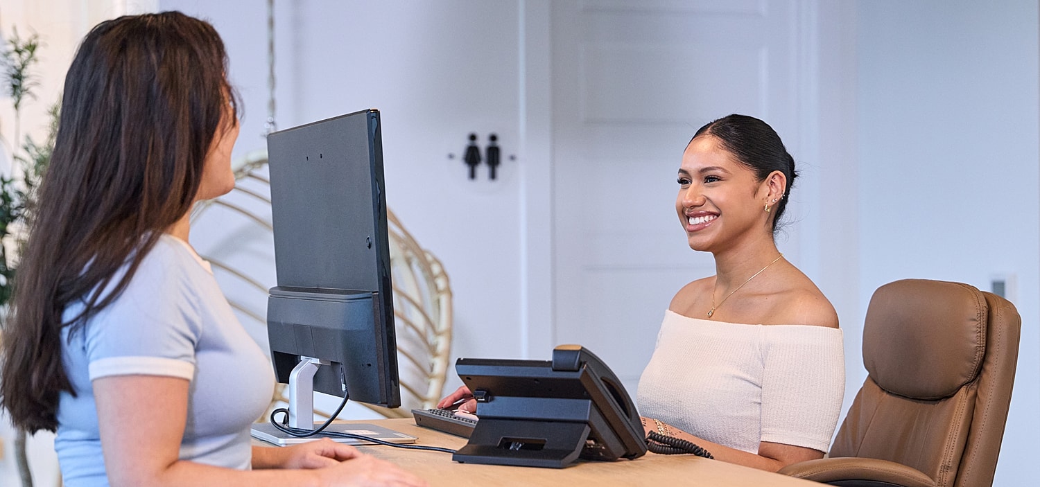 Receptionist assisting a visitor at the front desk.