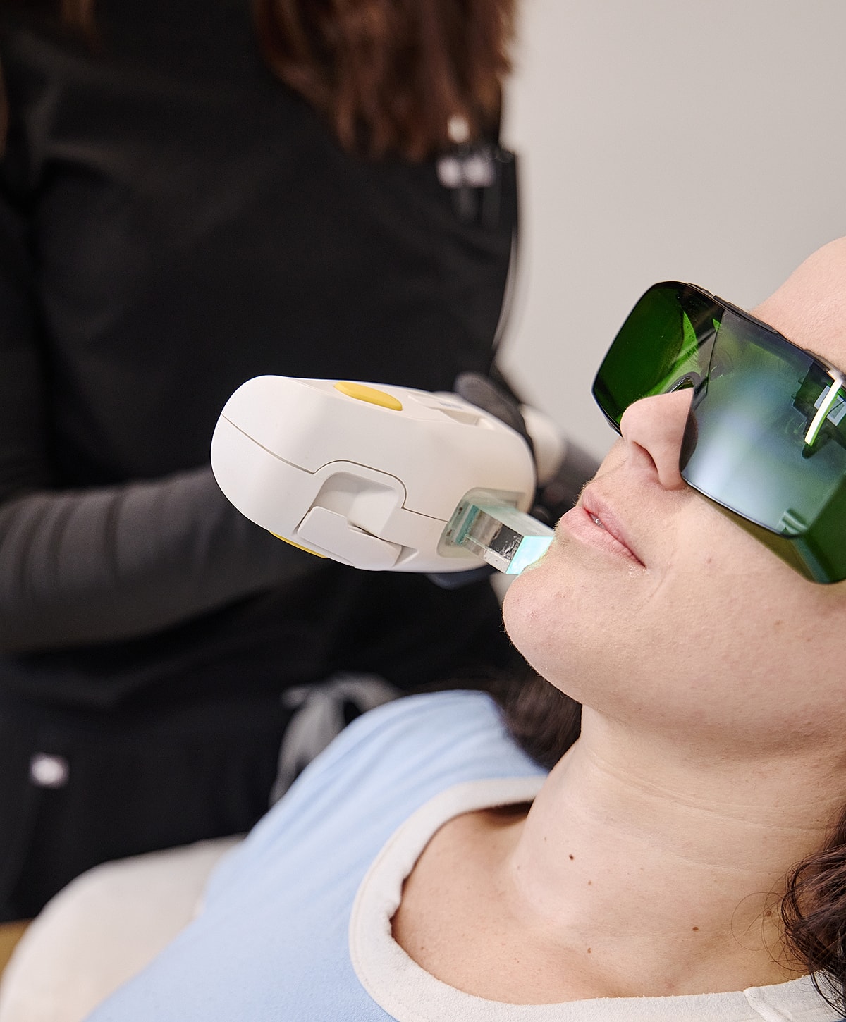 Woman receiving facial treatment with laser device.