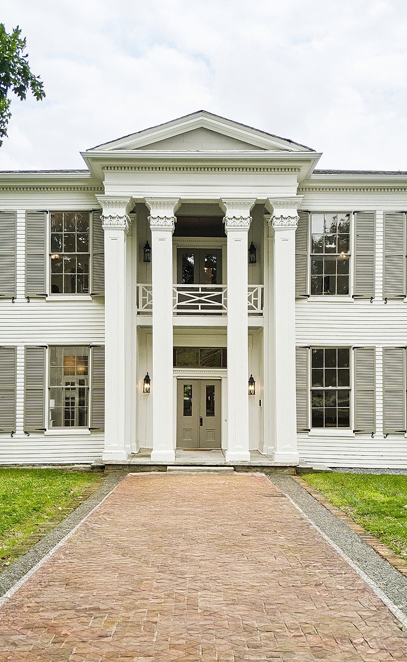 Historic white mansion with columns and pathway.