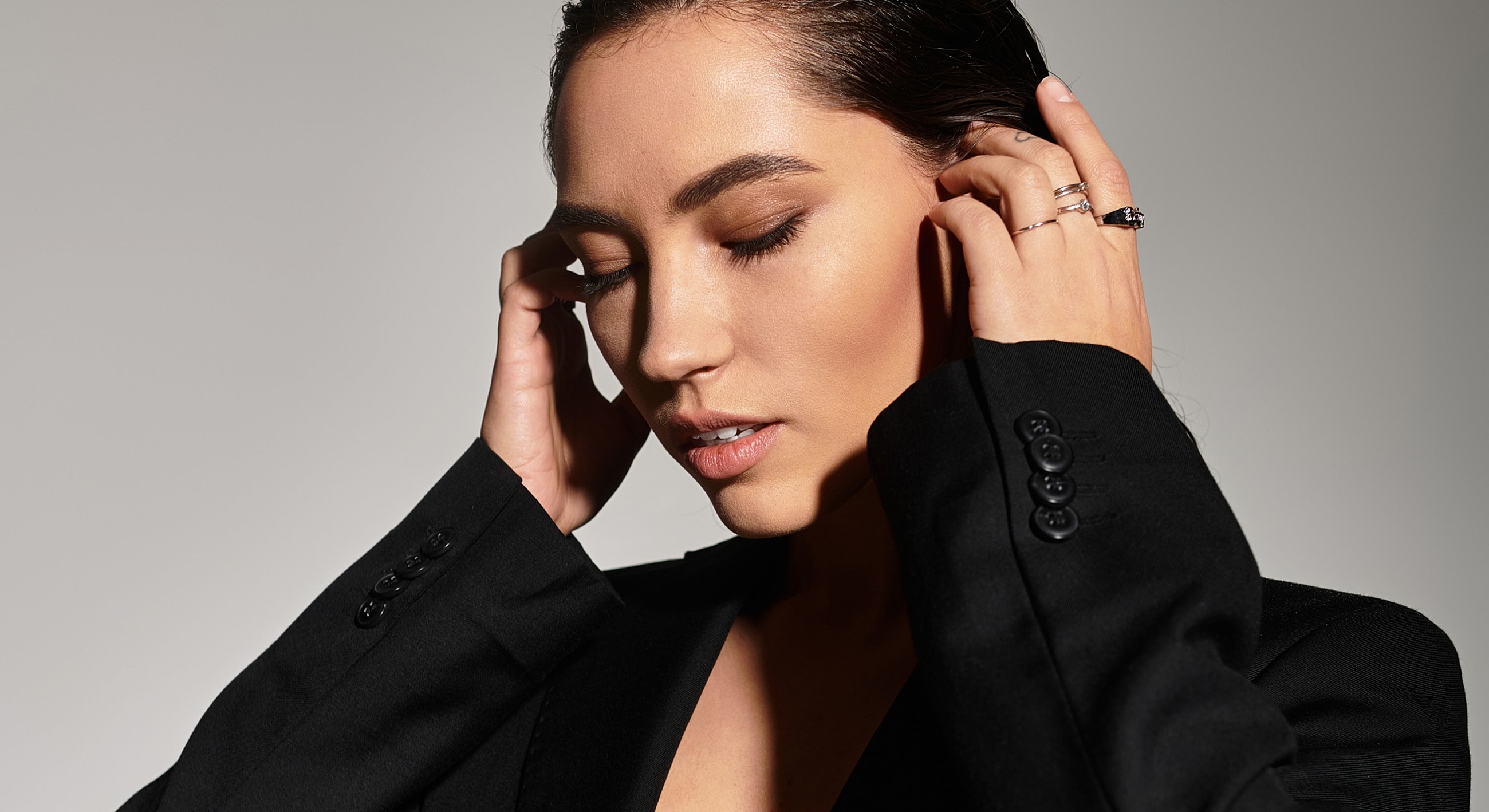 Model in black blazer with elegant pose.