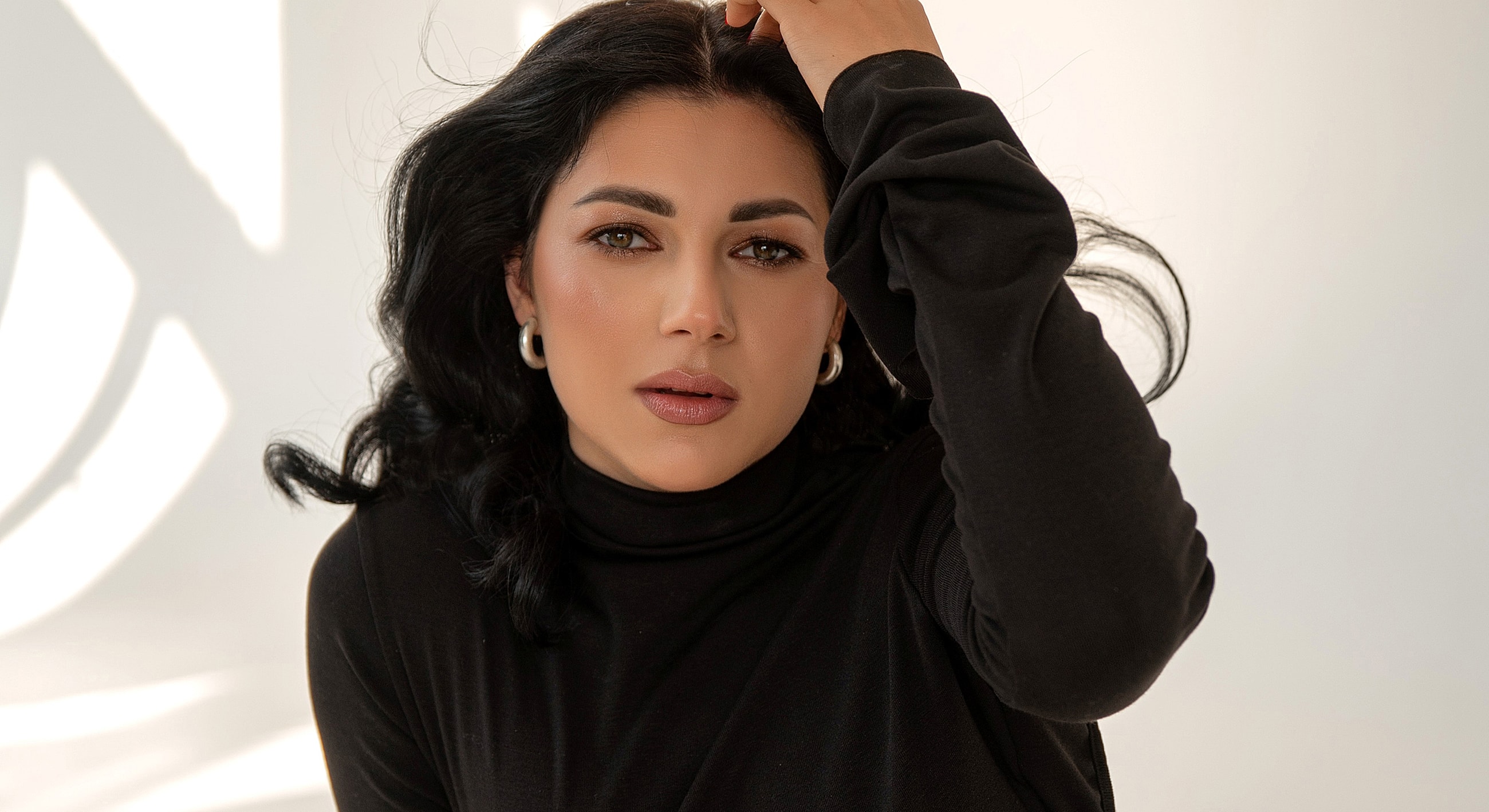 Woman in a black top with wavy hair.