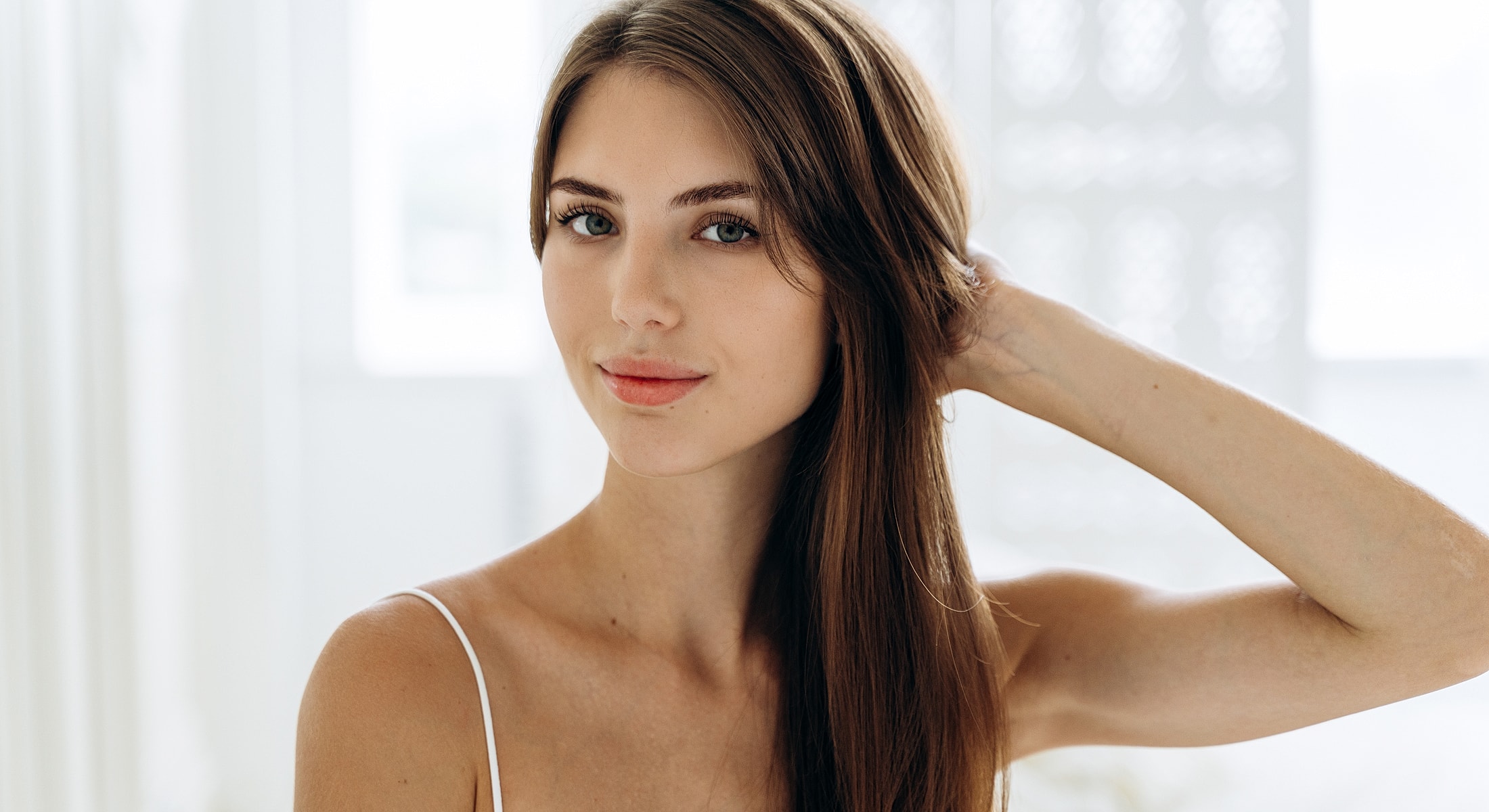 Young woman with long hair in bright room.