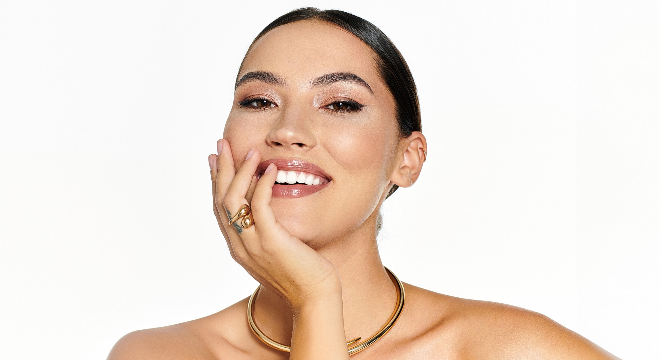 Smiling woman with jewelry and radiant makeup.
