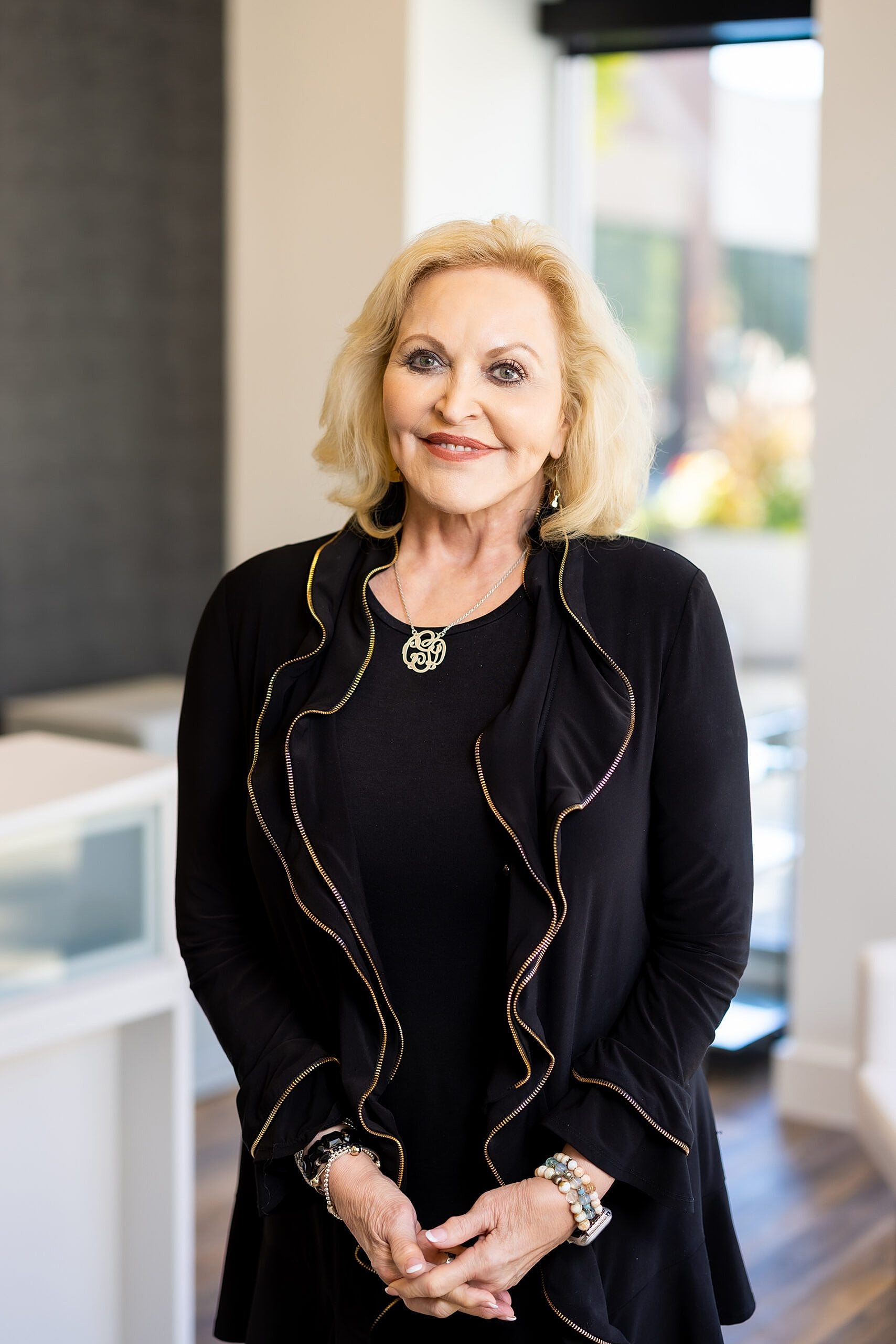 Smiling woman in black outfit with stylish accessories.