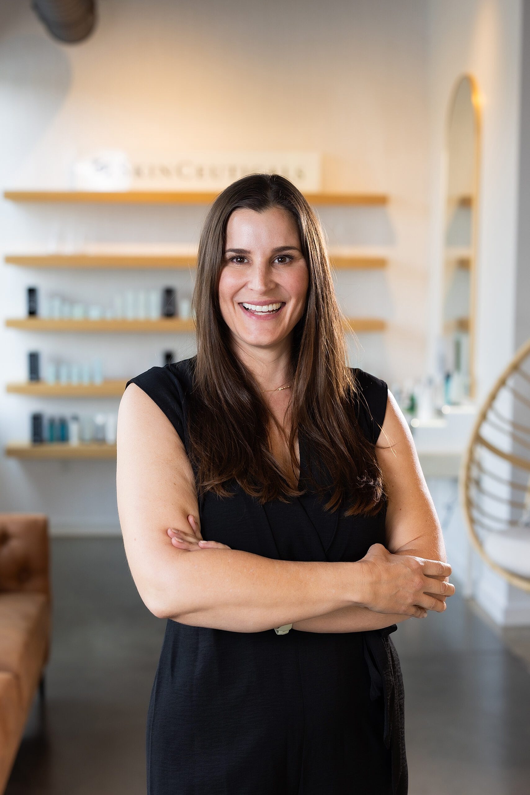 Smiling woman in professional setting with crossed arms.