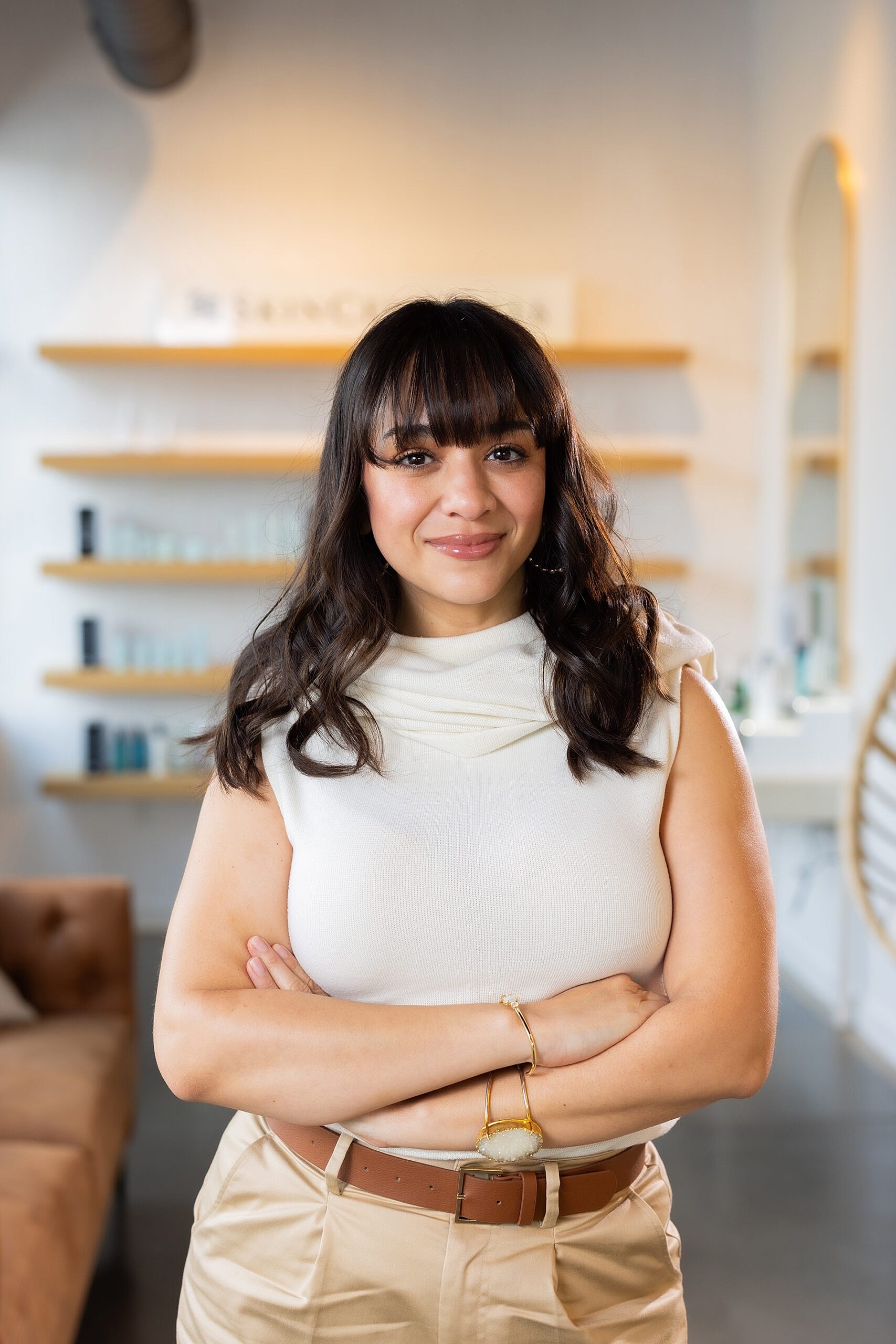 Smiling woman with crossed arms in modern setting.